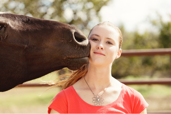 a horse kissing a young girl